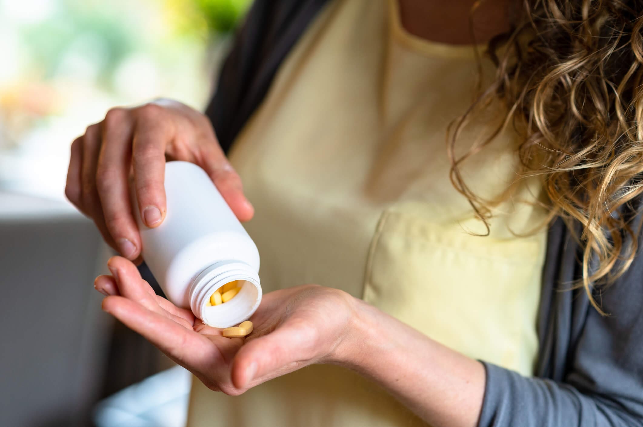 Person pouring pills from a bottle.